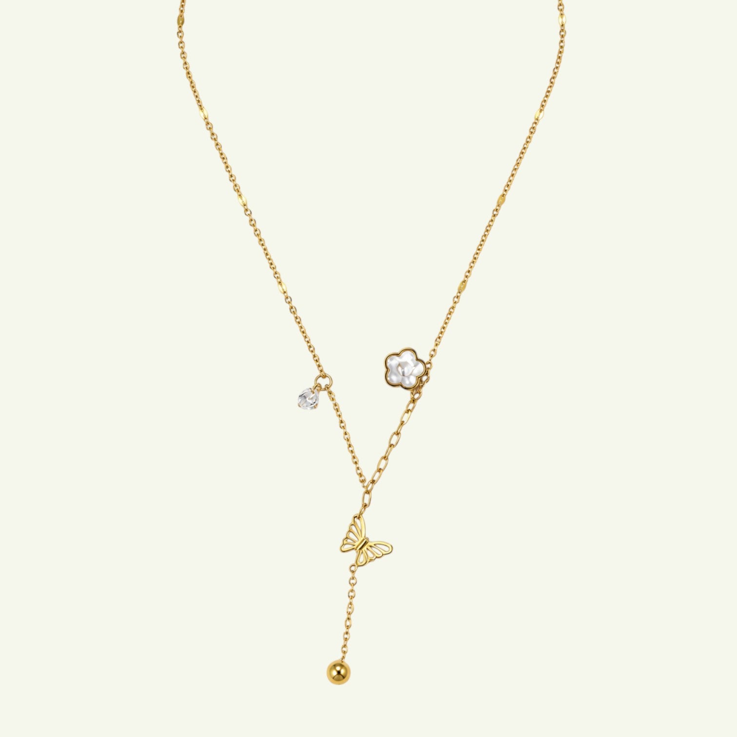 Anzora Jewel gold-toned lariat necklace featuring a butterfly charm, floral blossom, crystal accent, and spherical bead.