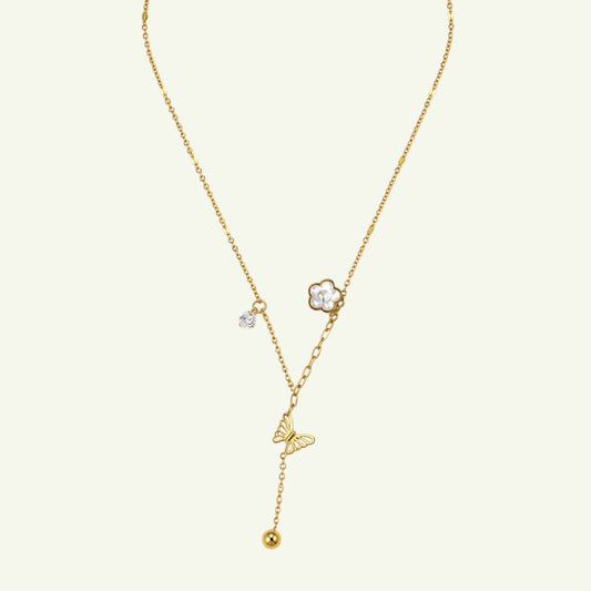 Anzora Jewel gold-toned lariat necklace featuring a butterfly charm, floral blossom, crystal accent, and spherical bead.