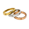Anzora Jewel Cipher Ring Set featuring three polished bands in gold, silver, and rose-gold with engraved emblems.