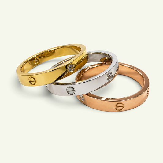 Anzora Jewel Cipher Ring Set featuring three polished bands in gold, silver, and rose-gold with engraved emblems.