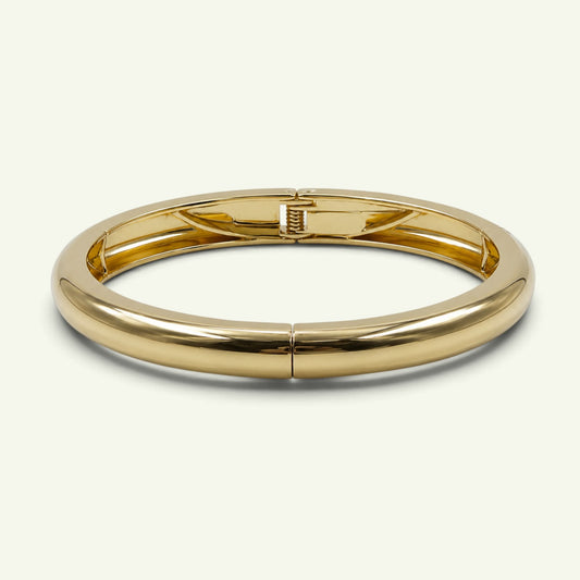 Anzora Jewel Luna Cuff bracelet in polished gold-toned metal with a sleek, rounded hinged silhouette.