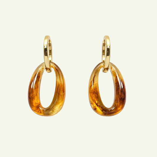 Anzora Jewel Nebula earrings featuring polished gold hoops with dangling amber-toned marbled resin oval pendants