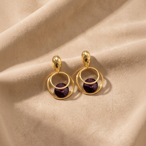 Anzora Jewel Orbit statement earrings featuring hammered gold studs, double hoops, and deep purple faceted crystals.